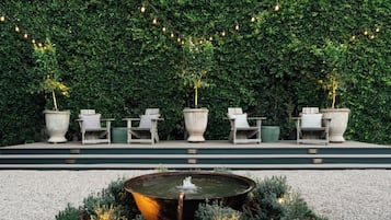 Relax and socialize in this serene outdoor seating area, featuring comfortable chairs and tables amidst lush greenery and a soothing fountain.