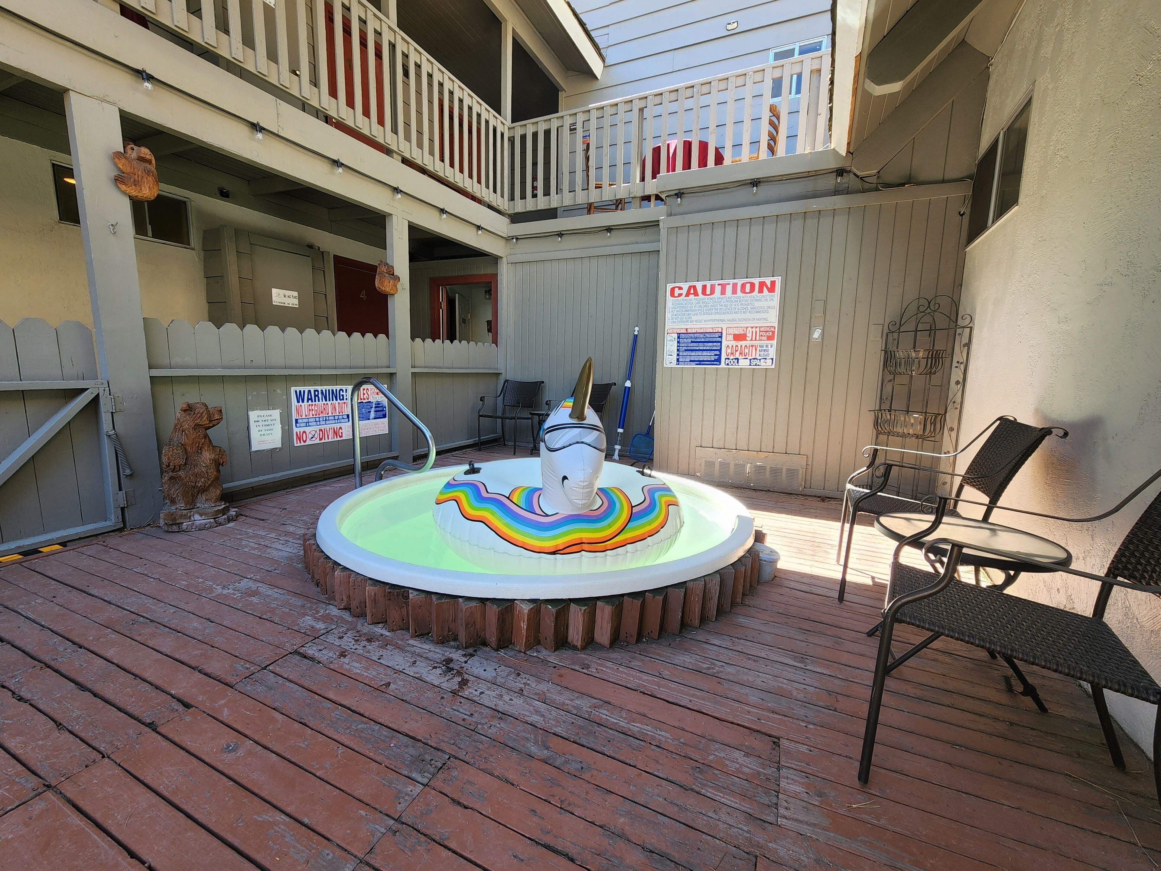 A pool area with a caution sign, a lifeguard chair, and a wooden fence.
