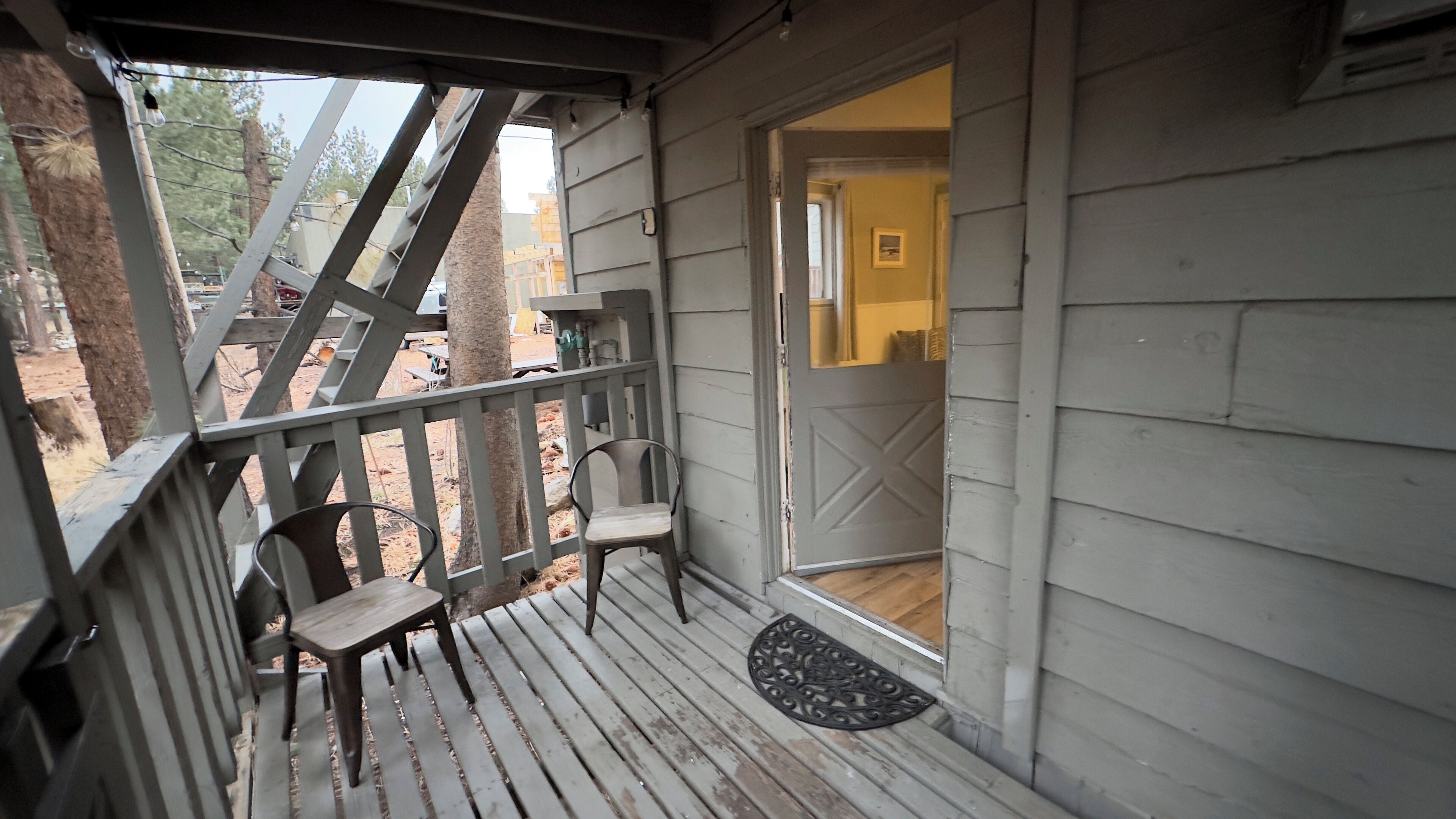 A wooden porch with two chairs and a doormat.