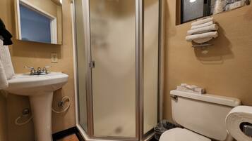 A bathroom with a glass-enclosed shower, a sink, and a toilet.