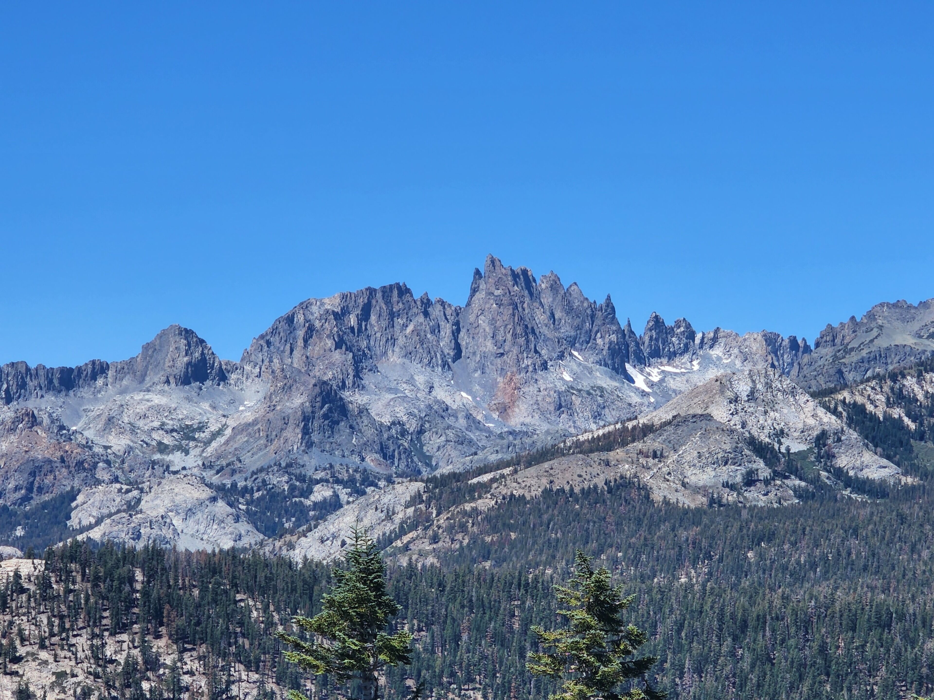A mountain landscape with rugged peaks and dense forest.