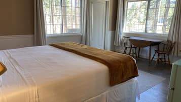 Una habitación de hotel con una cama grande, un escritorio de madera y dos sillas.