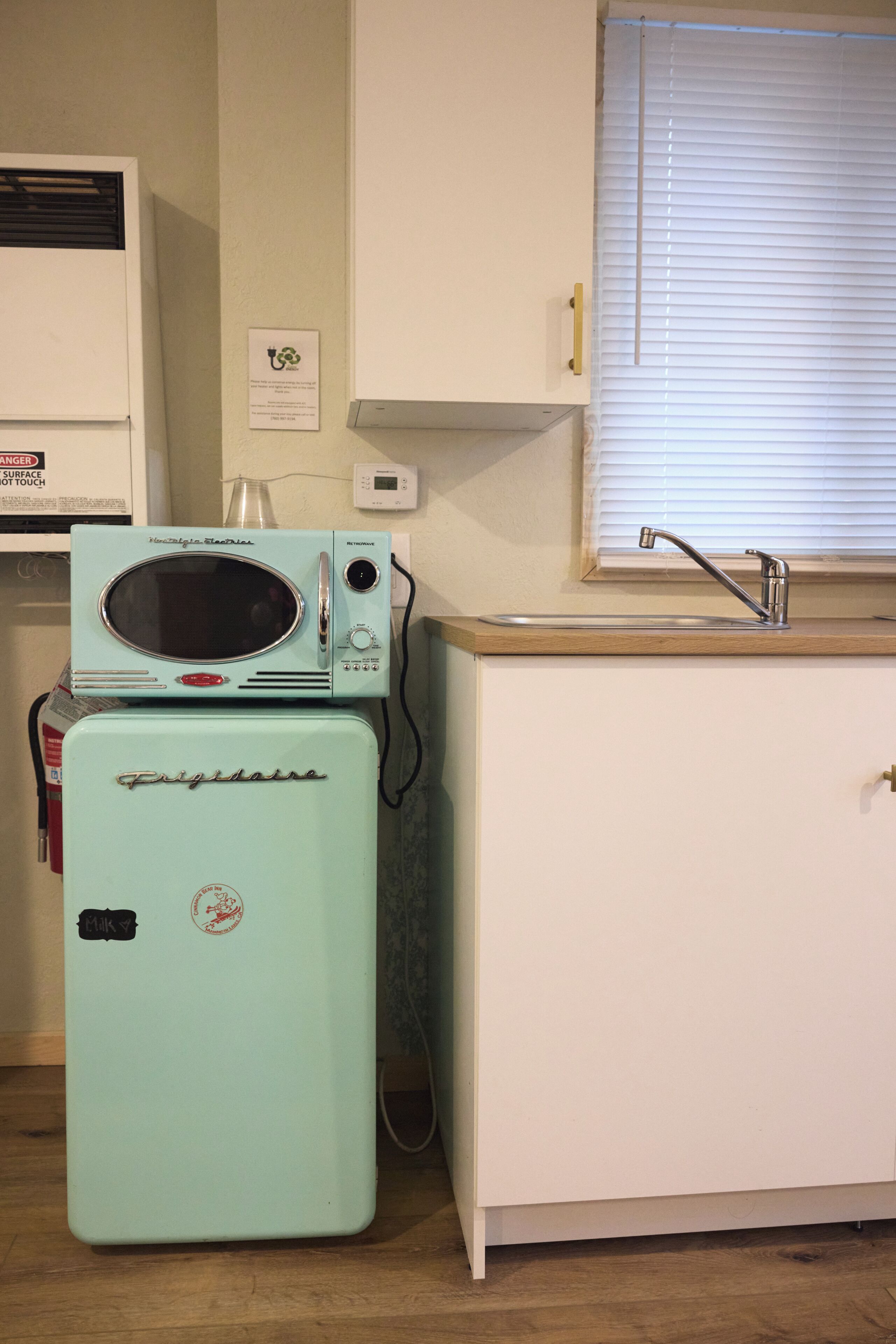 A compact kitchen with a vintage-style refrigerator, a microwave, and a sink.