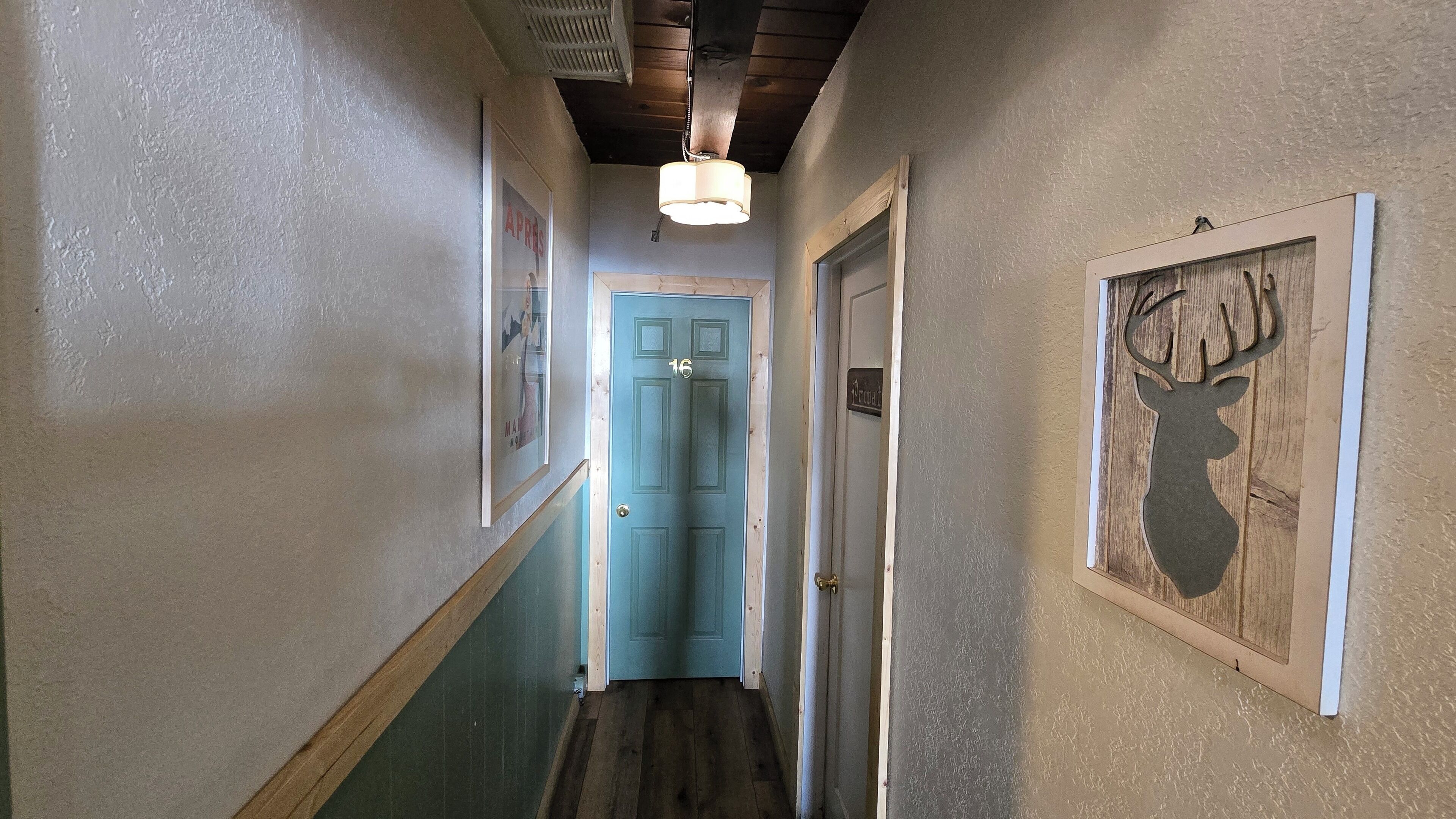 A hallway with a blue door, wooden floors, and a ceiling fan.