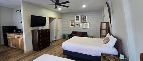 A bedroom with a bed, a dresser, a television, and a ceiling fan.