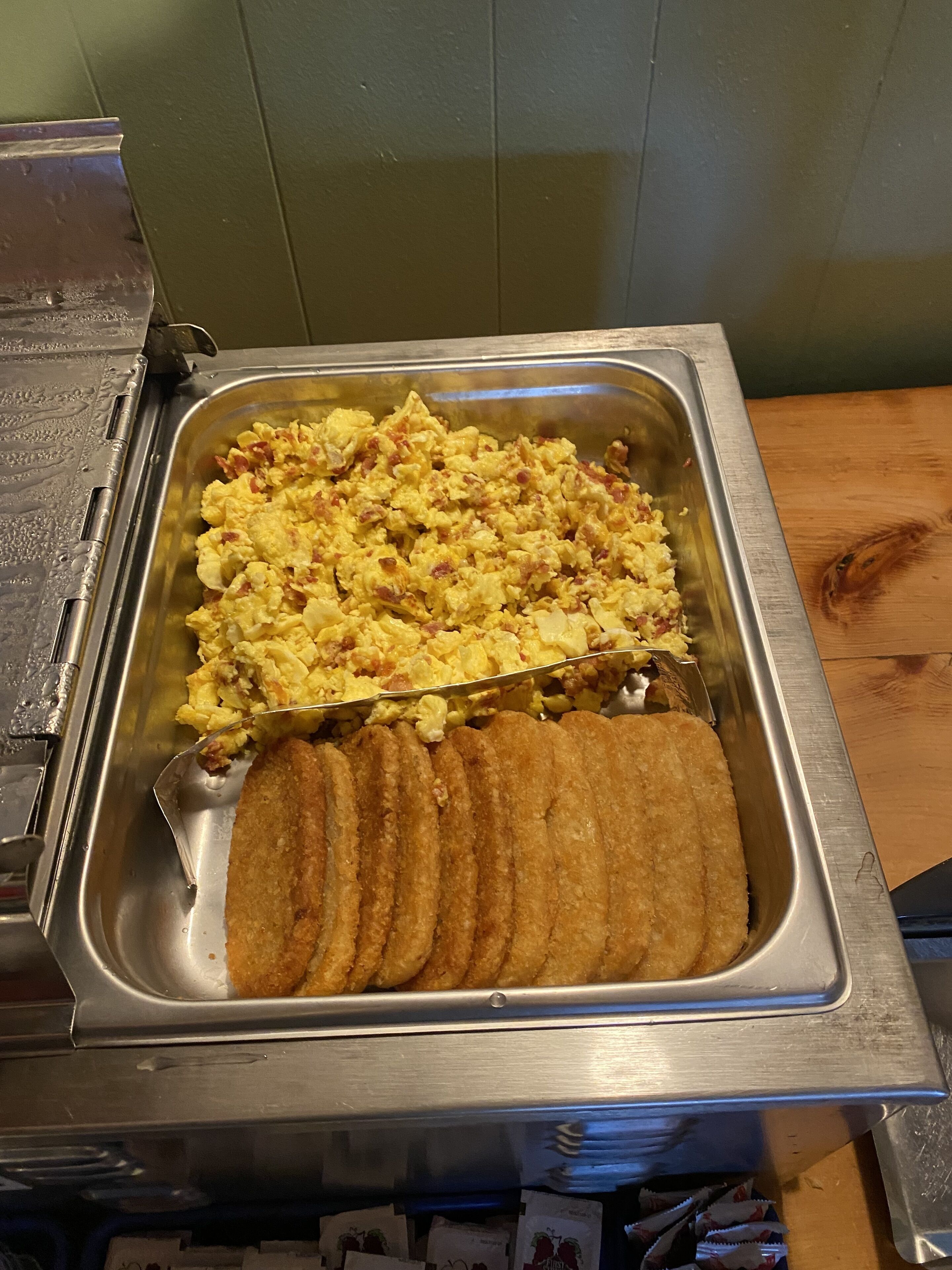A buffet with scrambled eggs and fried potatoes.