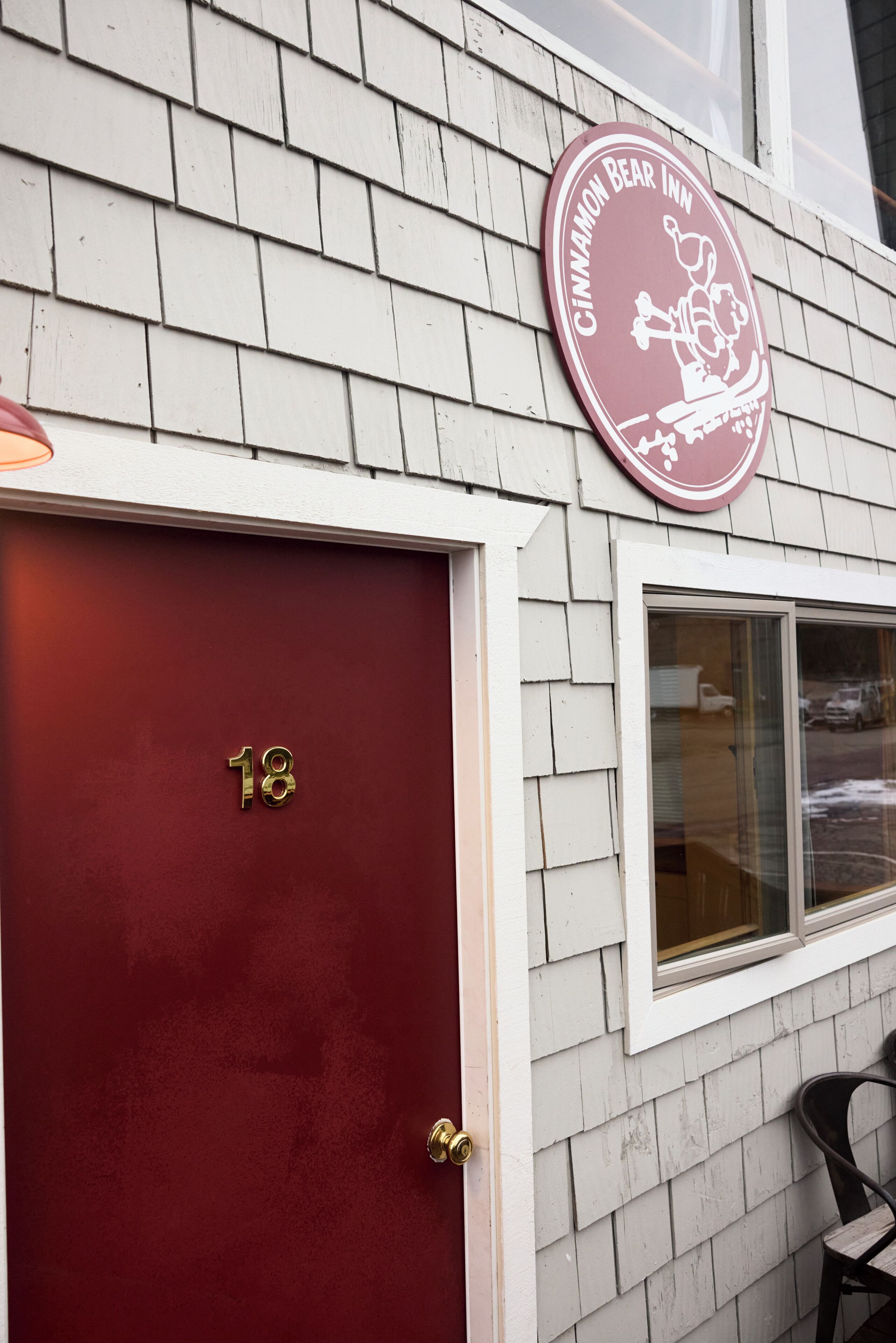 Un edificio con una puerta roja marcada con el número 18, una ventana y un letrero que indica Cinnamon Bear Inn.