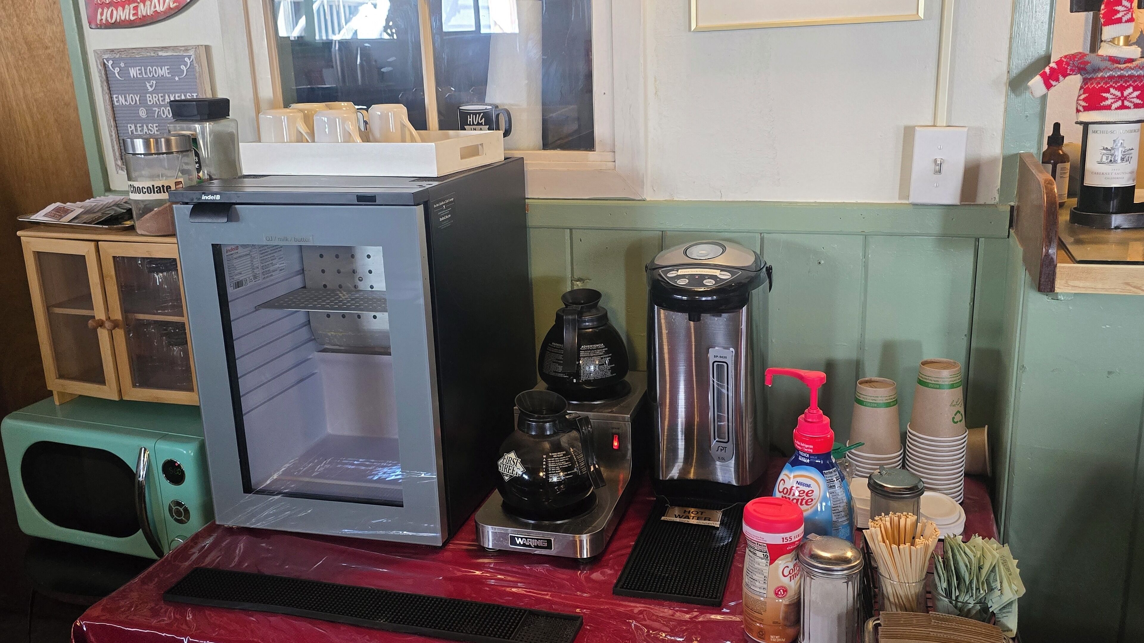 En kaffestation med kaffemaskine, mælkeskummer og forskellige kaffekopper samt beholdere.