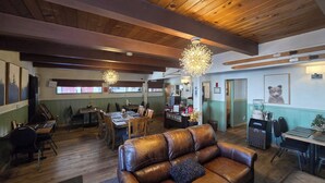 A cozy restaurant with wooden beams, leather seating, and pendant lighting. - Cinnamon Bear Inn (Mammoth Lakes)