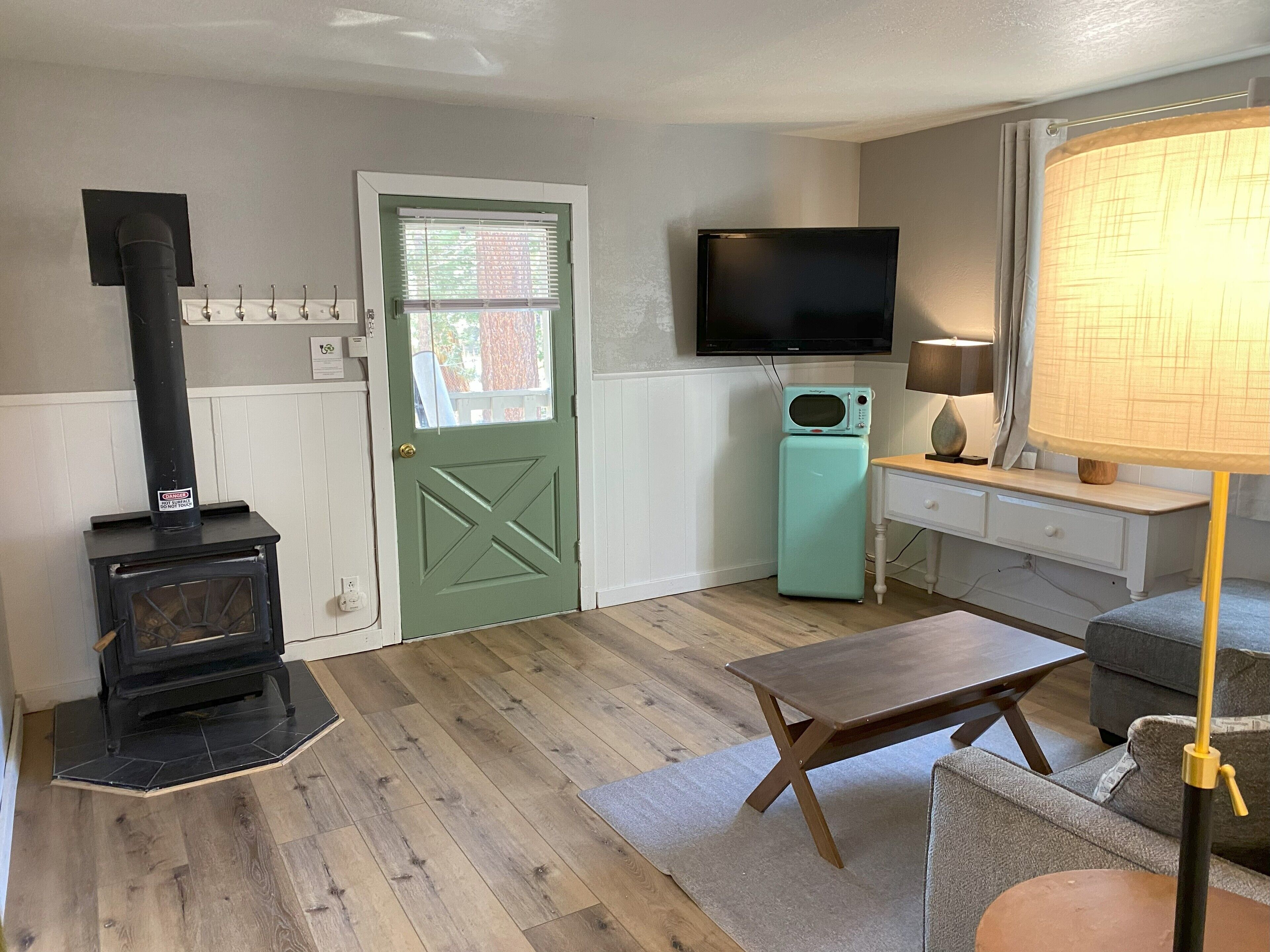 A living room with a wood-burning stove, a television, a microwave, a lamp, and a sofa.