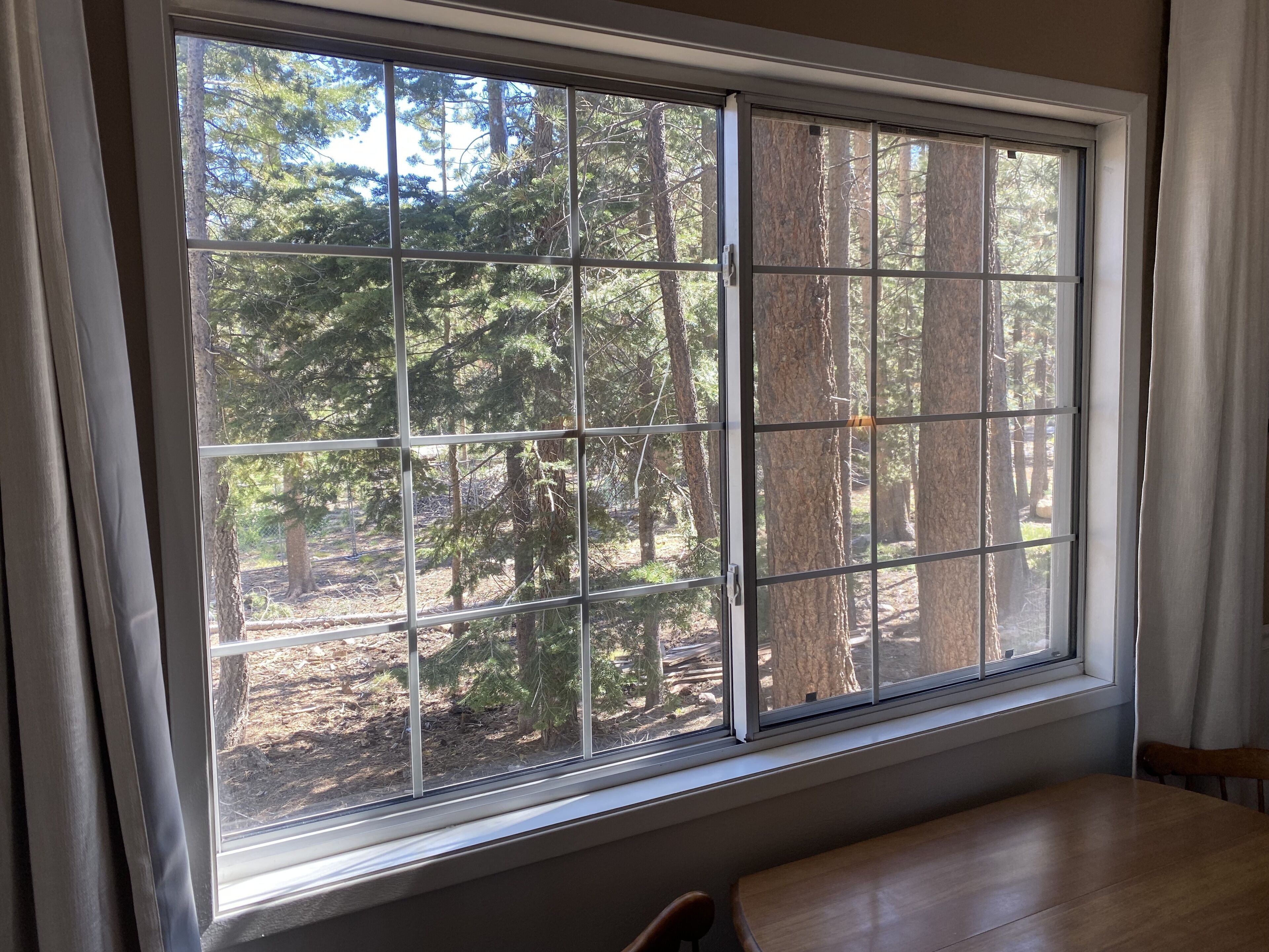 A room with a large window offering a view of a forested area.