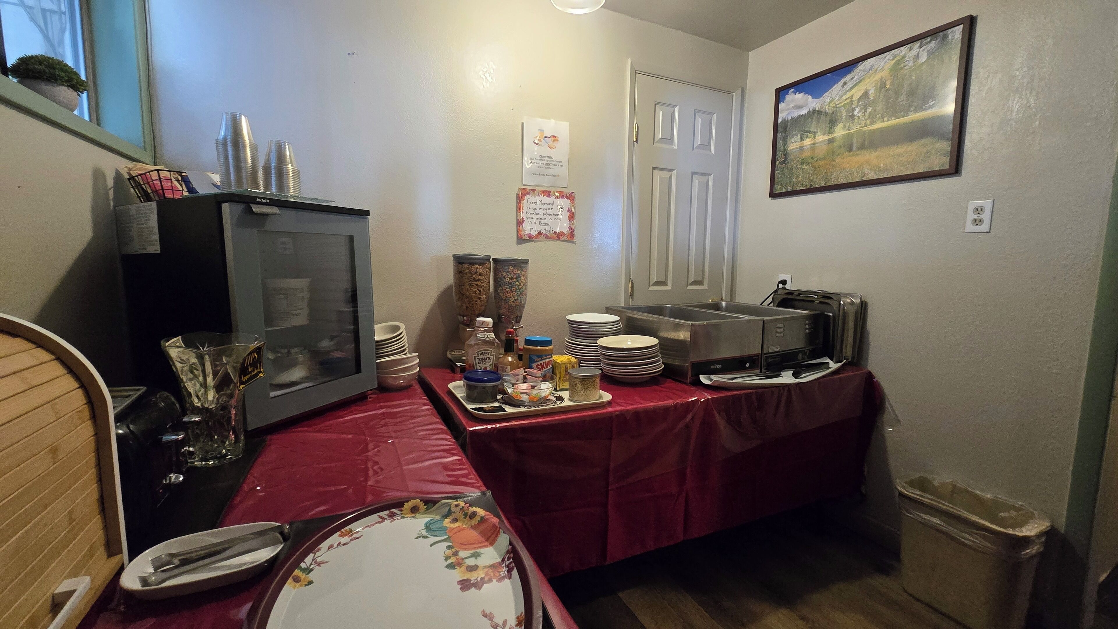 Una kitchenette pequeña equipada con refrigerador, microondas, tostadora y cafetera. Hay diversos alimentos y condimentos sobre la encimera.