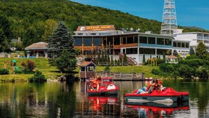 A lakeside view of a hotel with a dock, boats, and a mountain backdrop. - Indian Head Resort (Lincoln)