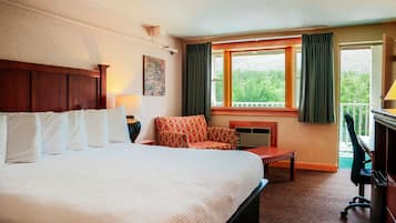 A hotel room with a large bed, a chair, a desk, a desk, and a window with curtains.