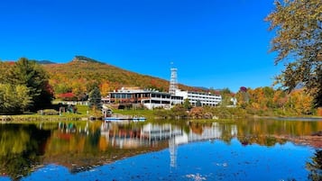 A building with a tower, a lake, and autumn foliage.