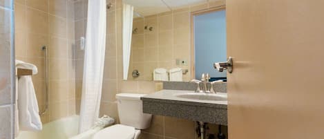 A bathroom with a shower, toilet, sink, and a mirror.