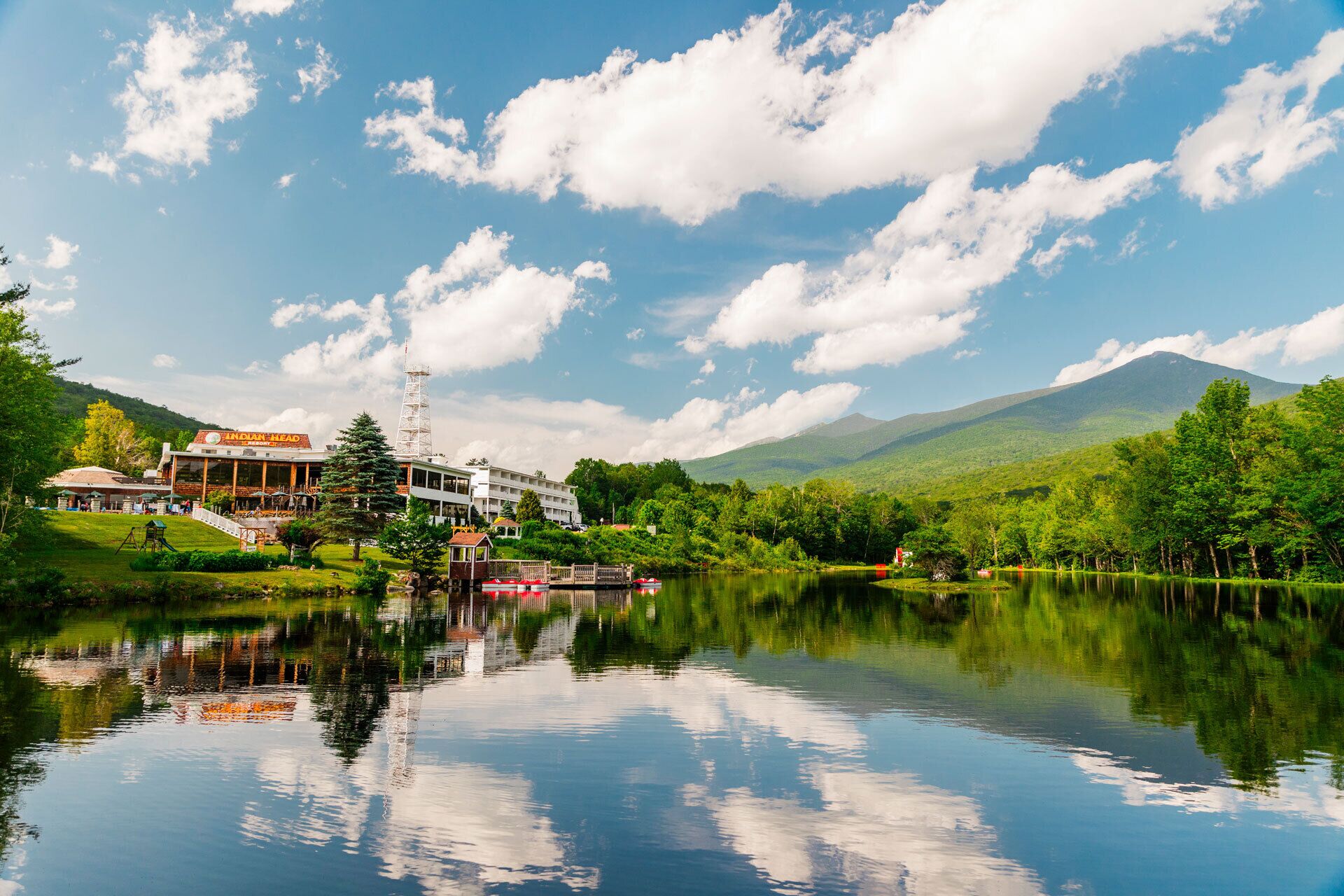 A hotel with a large building, a dock, and a lake with mountains in the background.