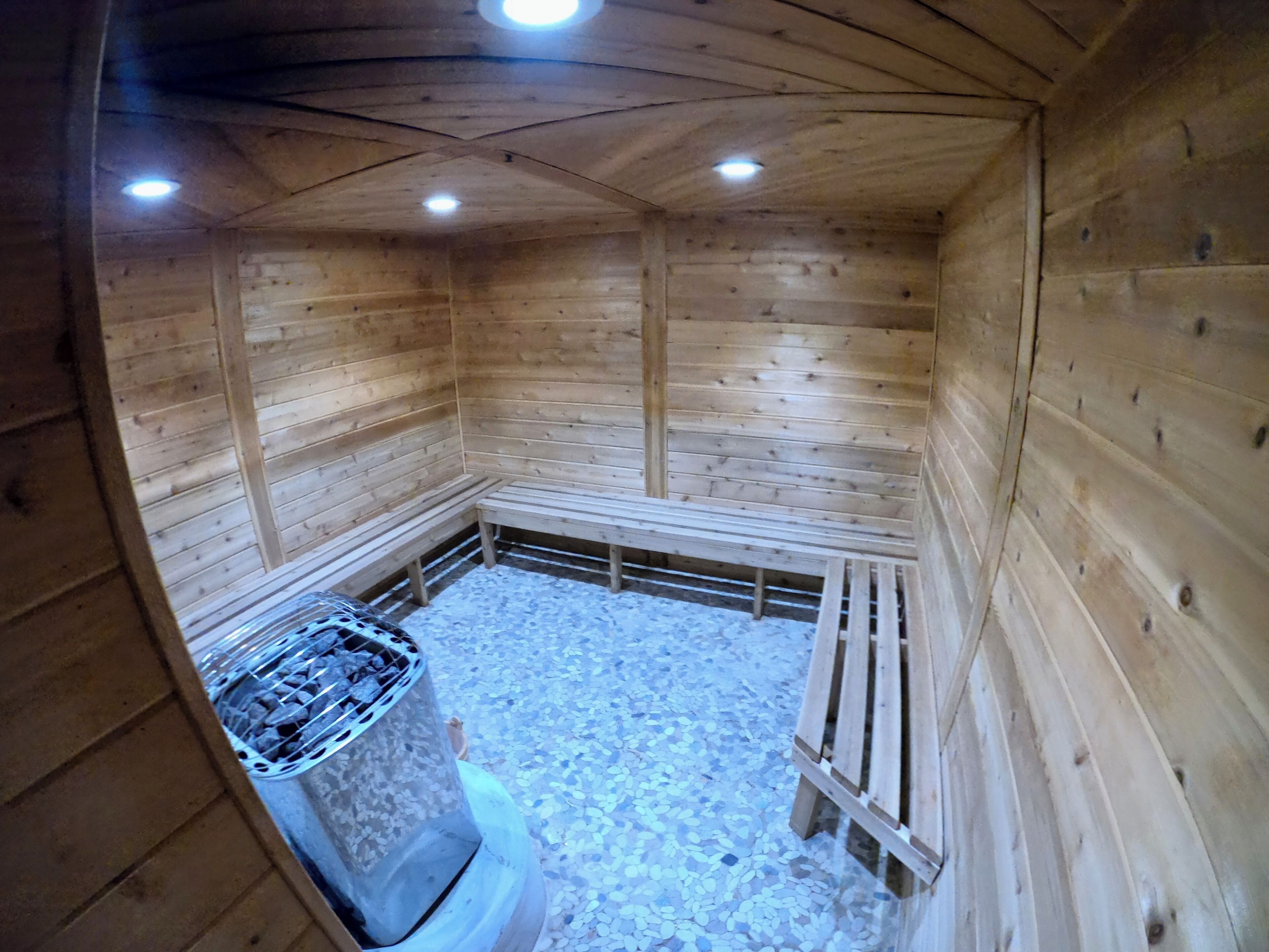 A sauna with wooden walls and benches, a tiled floor, and a central heating unit.