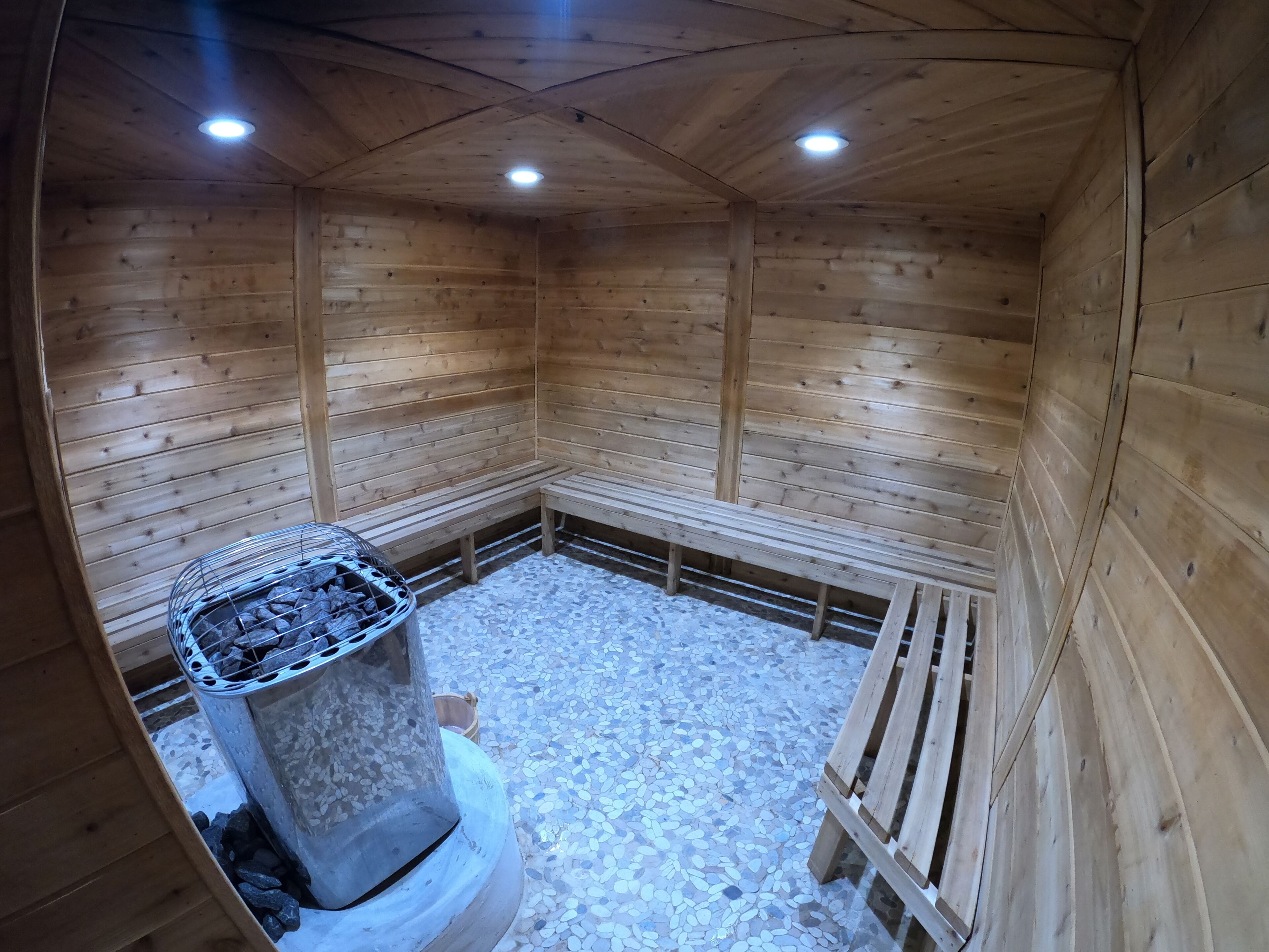 A wooden sauna with benches and a stone floor.