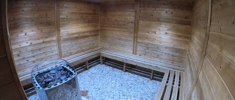 A wooden sauna with benches and a stone floor.
