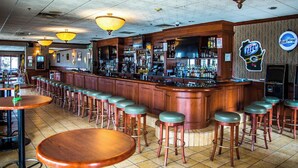 A bar area with wooden bar stools, a counter with a TV, and a sign for Blue Moon beer. - Hotel Mead Resorts & Conventions Center (Wisconsin Rapids)