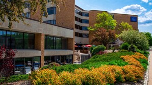 A hotel with a modern brick facade, outdoor seating area, and landscaped garden. - Hotel Mead Resorts & Conventions Center (Wisconsin Rapids)