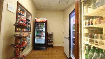 A corridor with a Coca-Cola refrigerator, snack vending machine, and a freezer stocked with beverages.