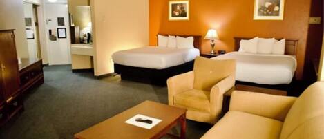 Een hotelkamer met twee bedden, een bank, een kleine tafel en een bureau met een lamp.