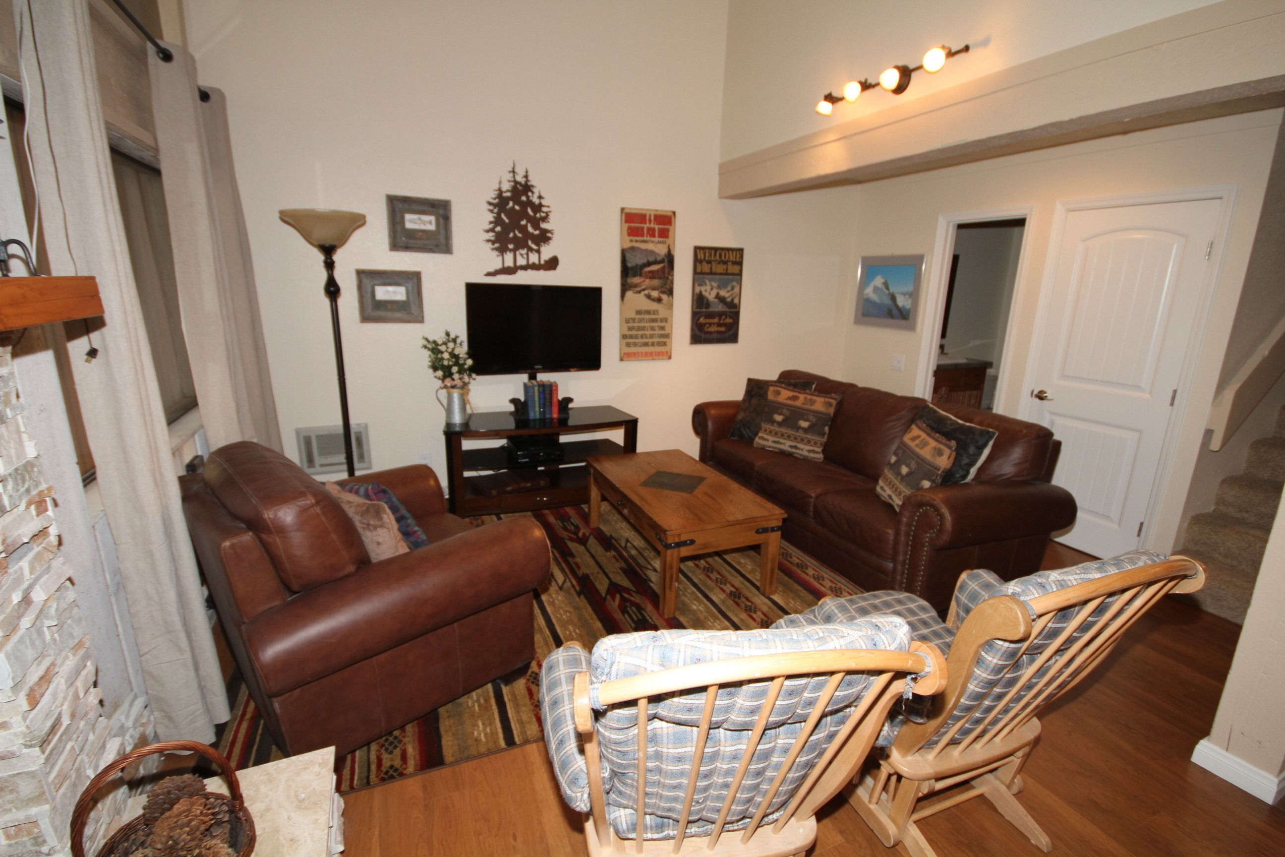 A living room with a brown leather sofa, a wooden coffee table, and a plaid armchair.