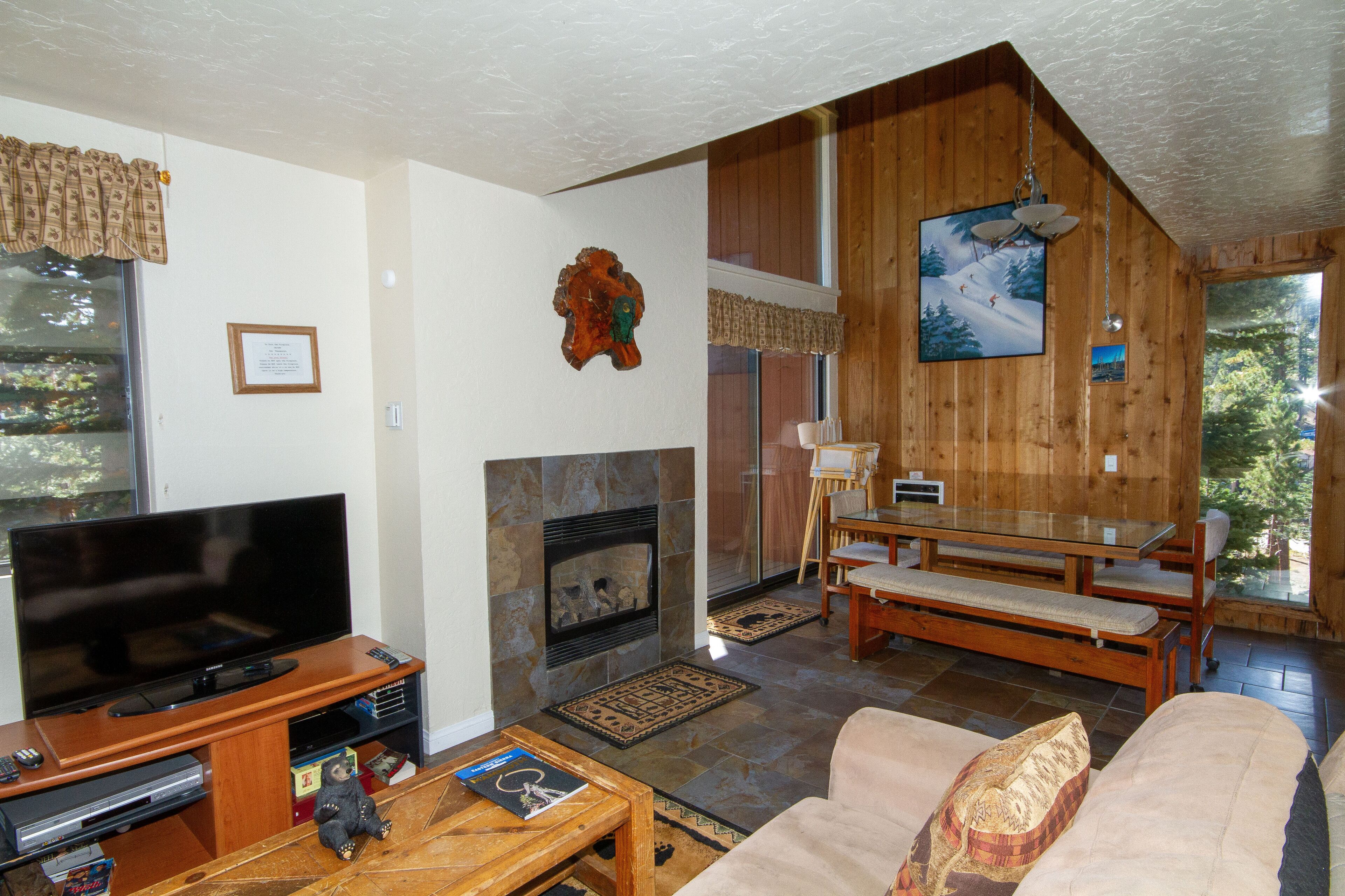 Una sala de estar acogedora con chimenea, televisor y comedor con muebles de madera.