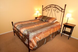 A neatly made bed with a striped bedspread, two bedside lamps, and a wooden headboard.