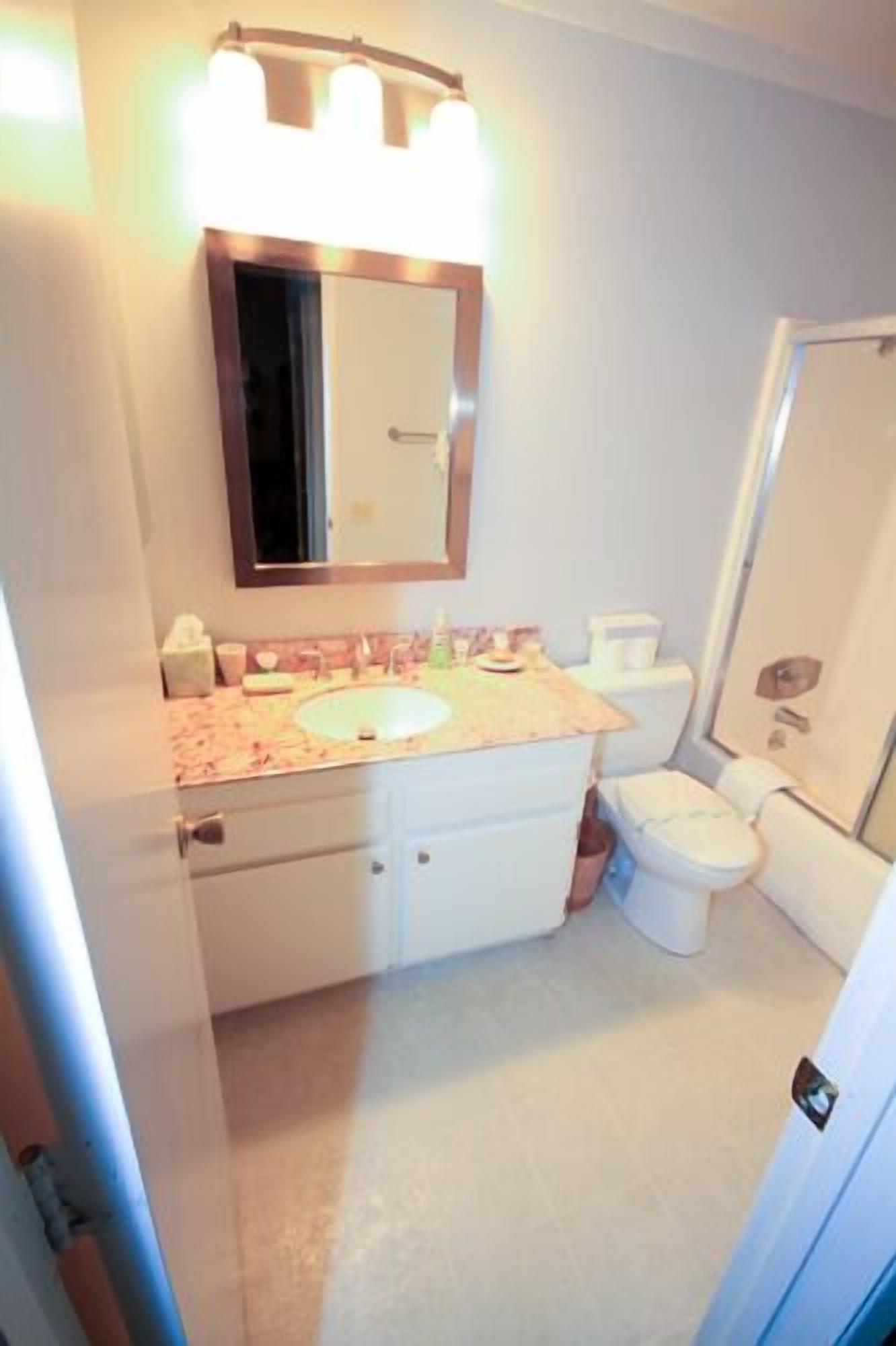A small bathroom with a white sink, a mirror above it, and a toilet.