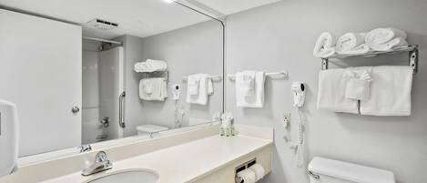 A modern bathroom with a large mirror, a sink, a toilet, and towel racks.