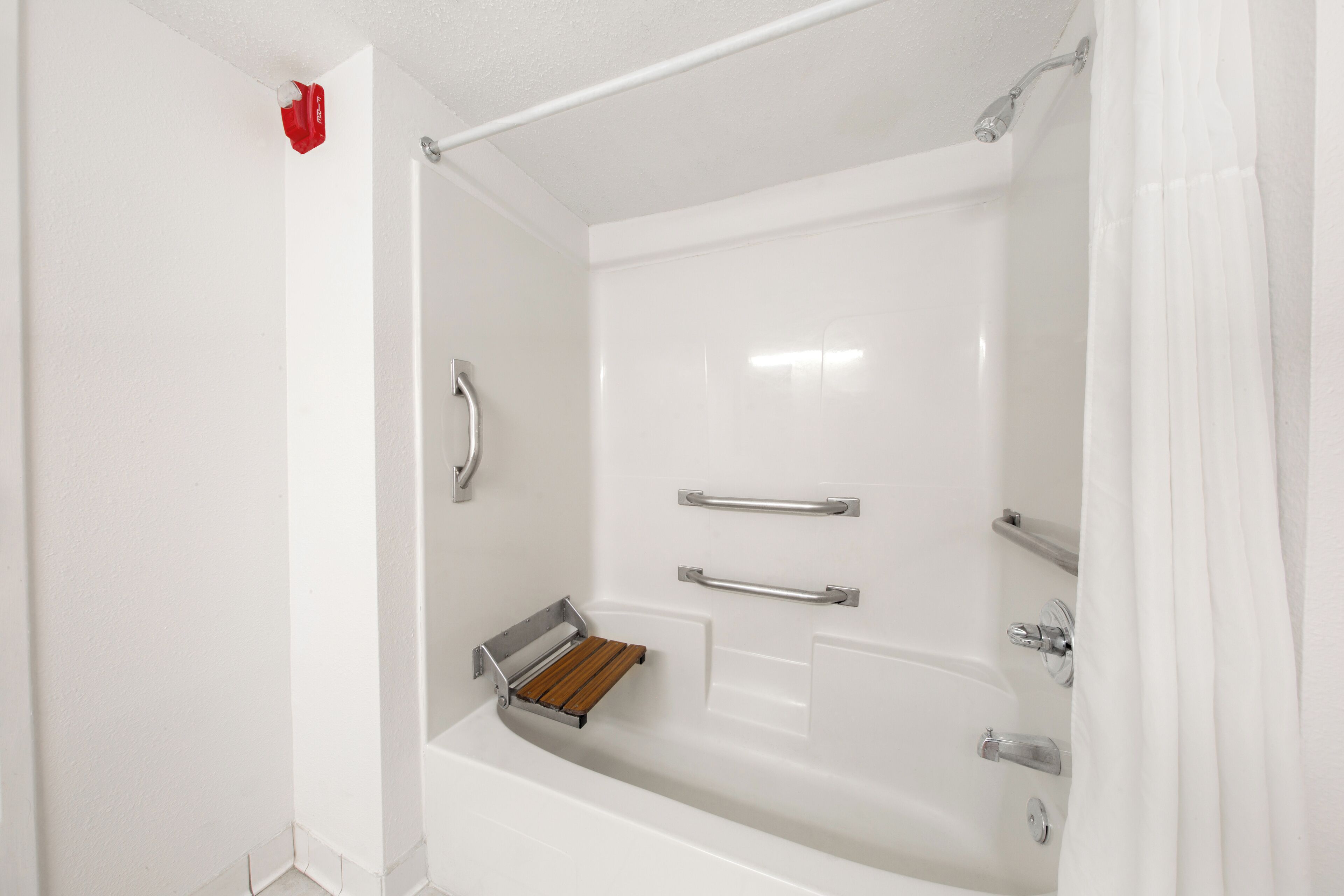 Un baño blanco con bañera, ducha y baranda.