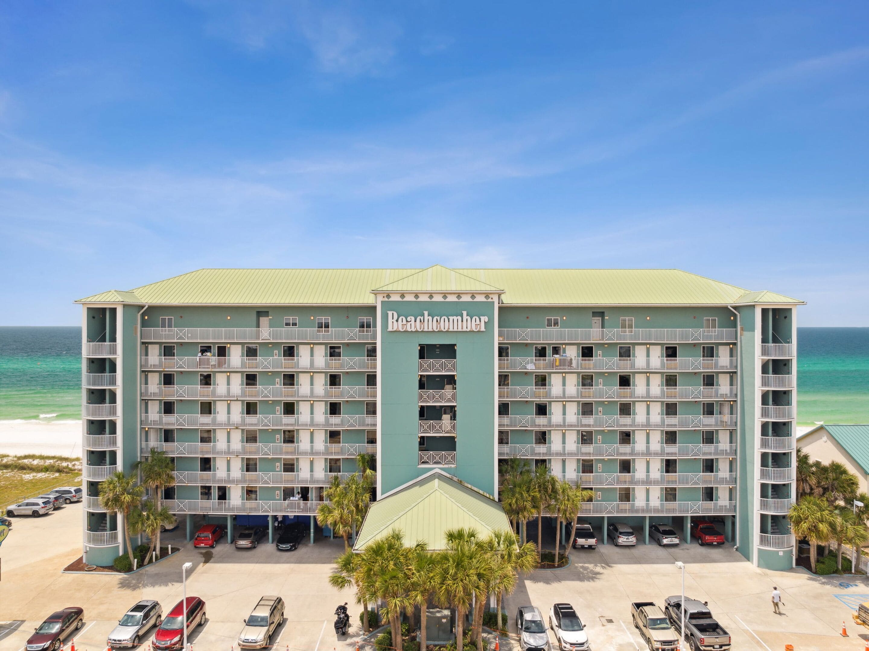 Un hotel de varios pisos con una entrada central, balcones y vistas al océano.