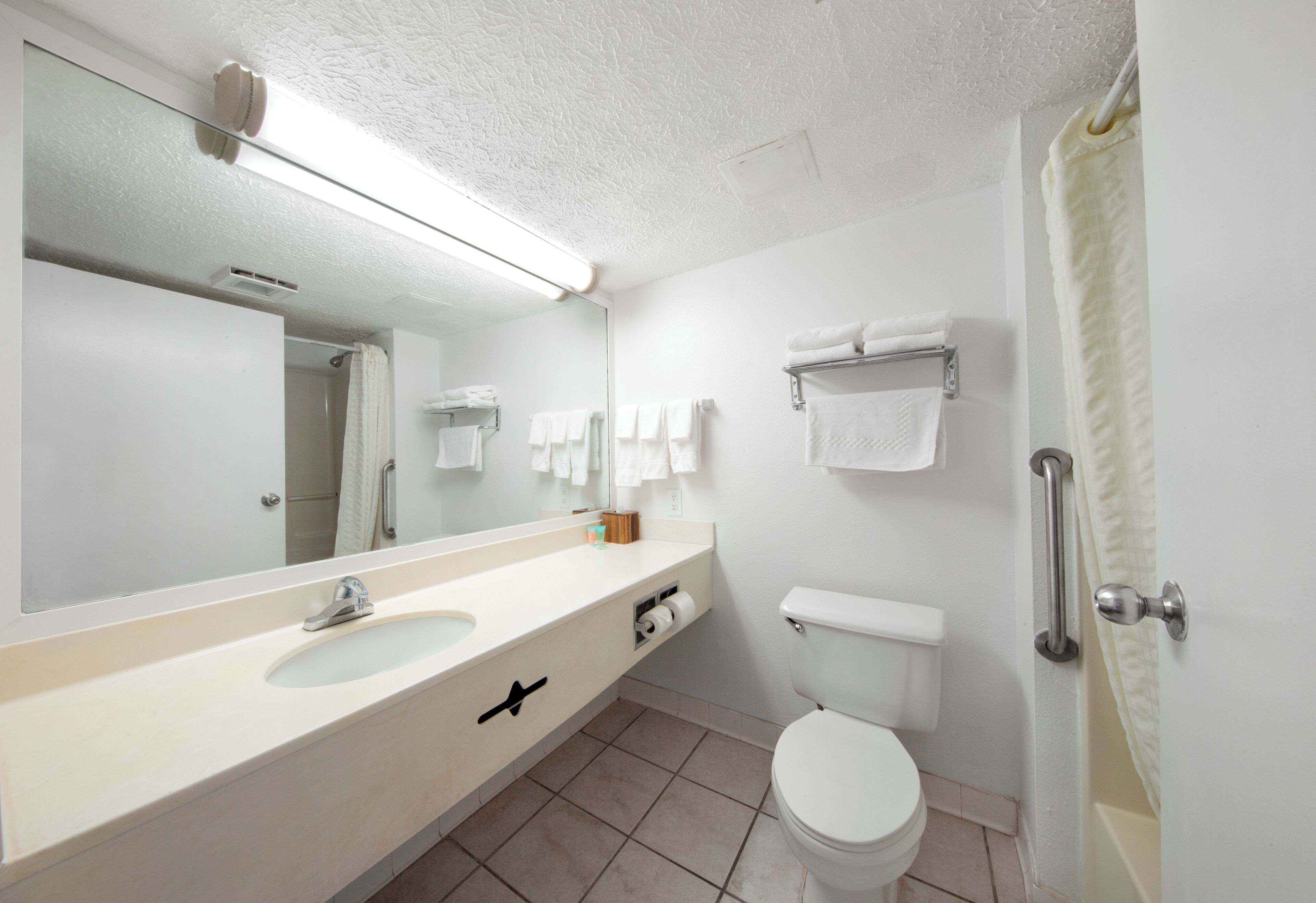 A modern bathroom with a large mirror, two sinks, a toilet, and a shower area.