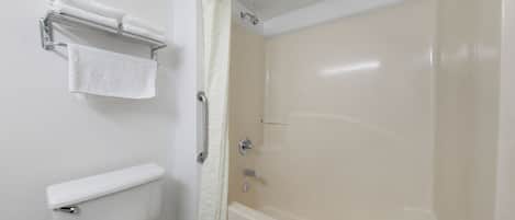 Ein Badezimmer mit Toilette, Handtuchhalter mit gefalteten Handtüchern und einer Badewanne.