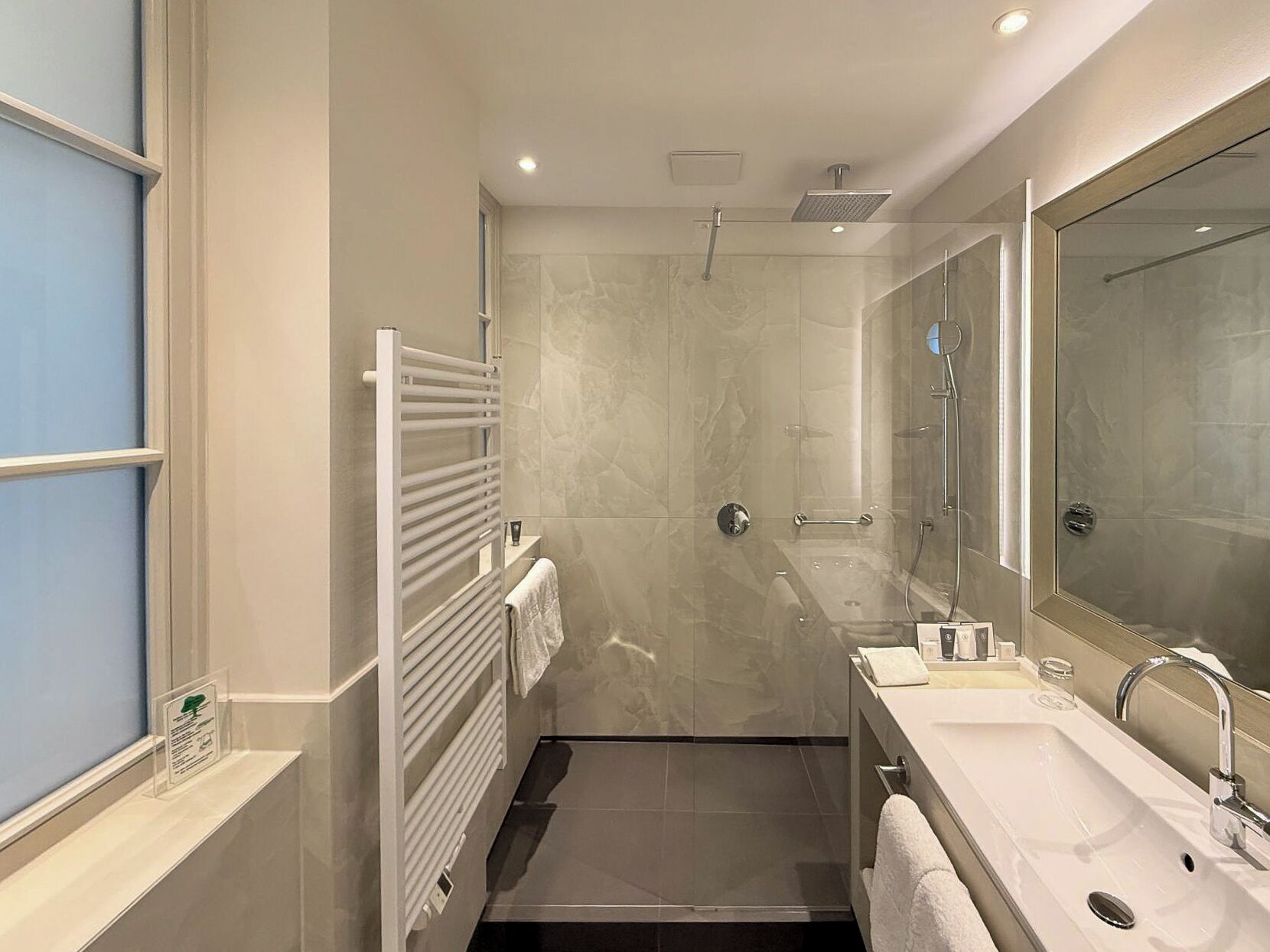 A modern bathroom with a walk-in shower, a large mirror, and a dual sink vanity.