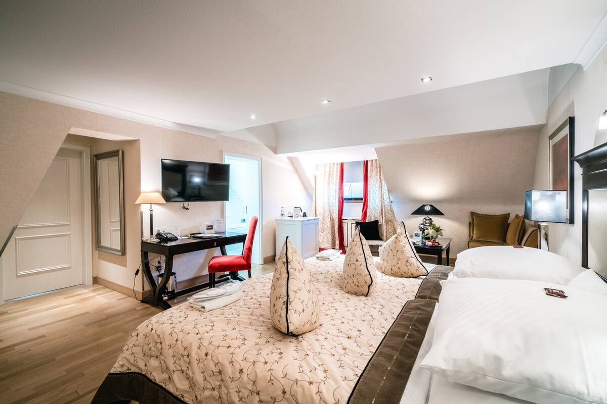 Una habitación de hotel con cama, escritorio, televisor y silla.