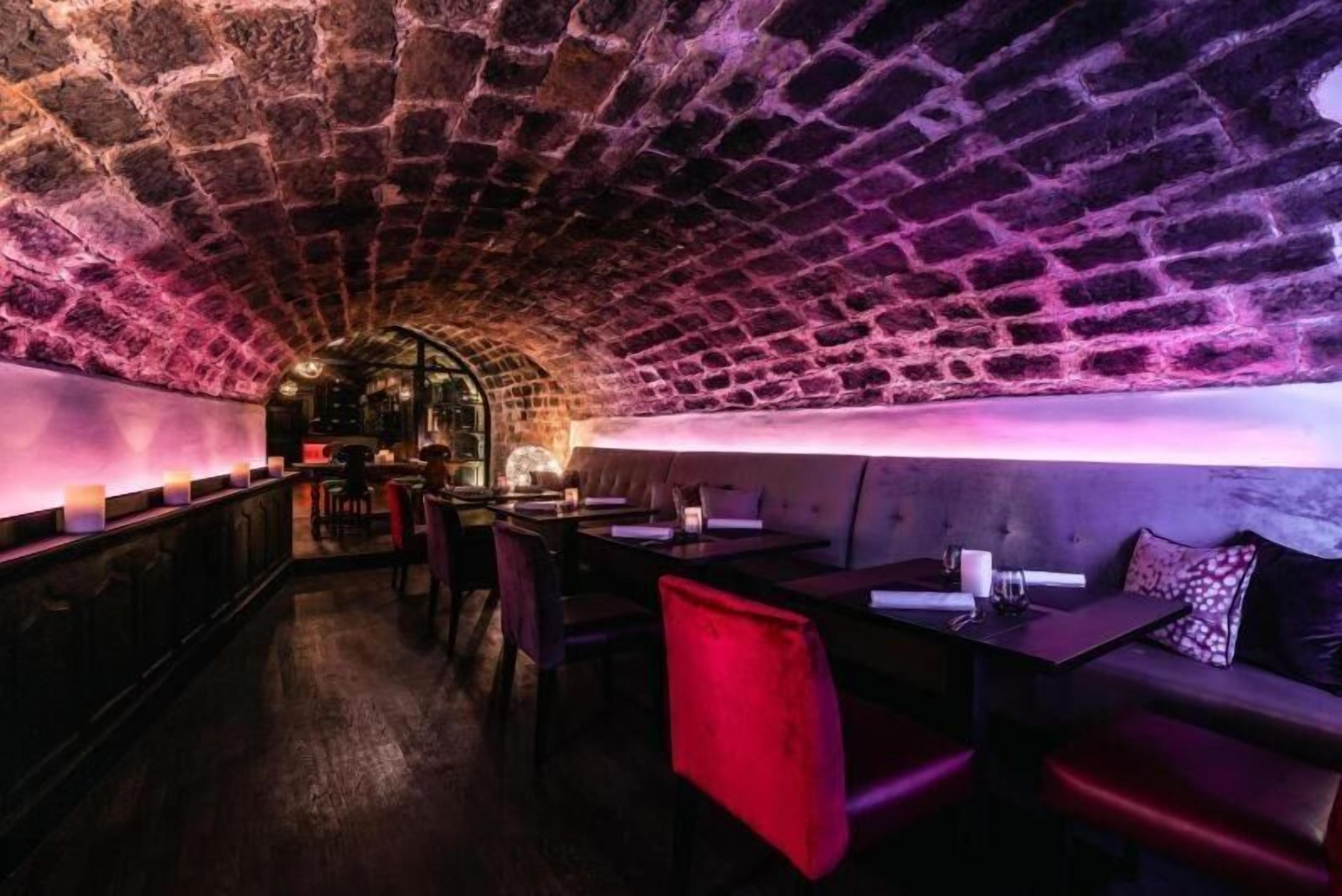 Un restaurante subterráneo con paredes de piedra y una decoración moderna.