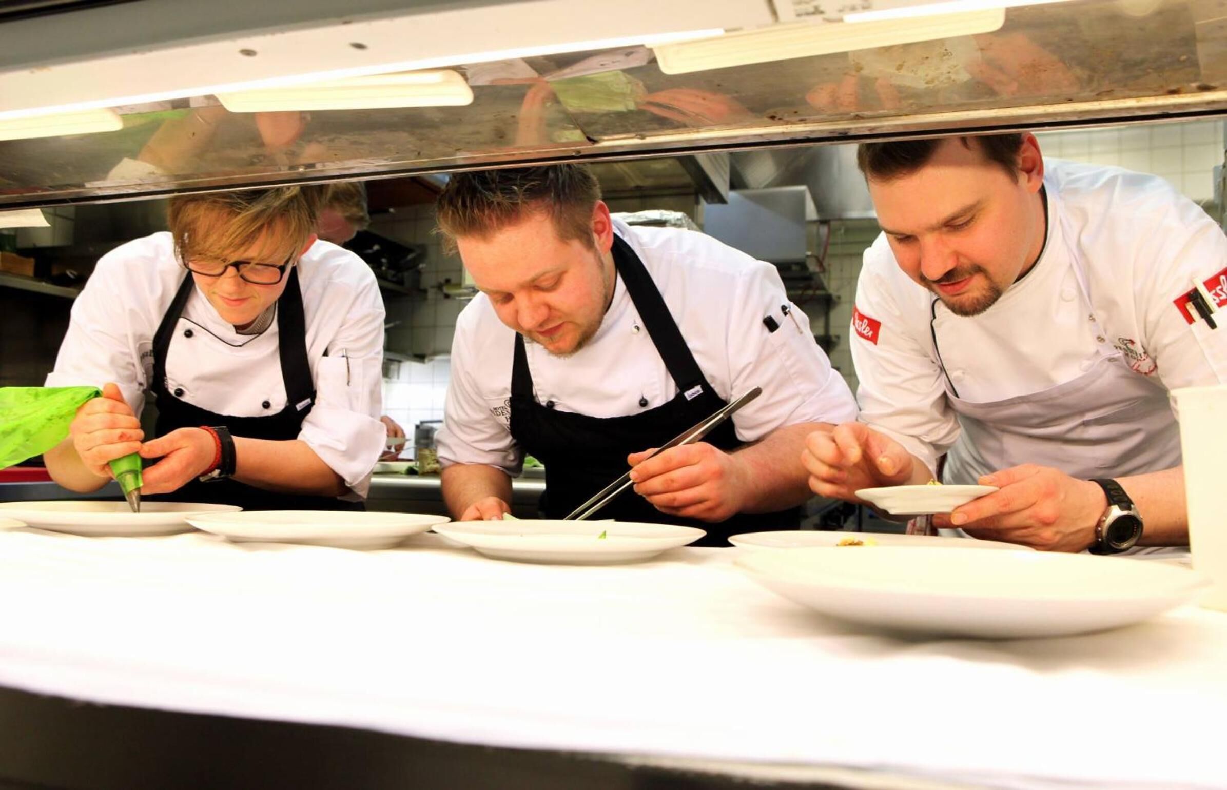 Chefs preparando comida en una cocina profesional.