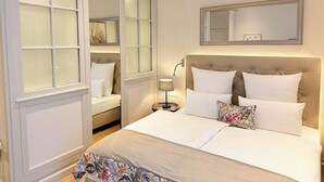 Un dormitorio con una cama grande, una mesita de noche, una lámpara, un espejo y una ventana con vidrio esmerilado.