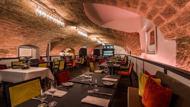 Un restaurante con mesas dispuestas para comer, con una pared de ladrillo rústica e iluminación moderna.
