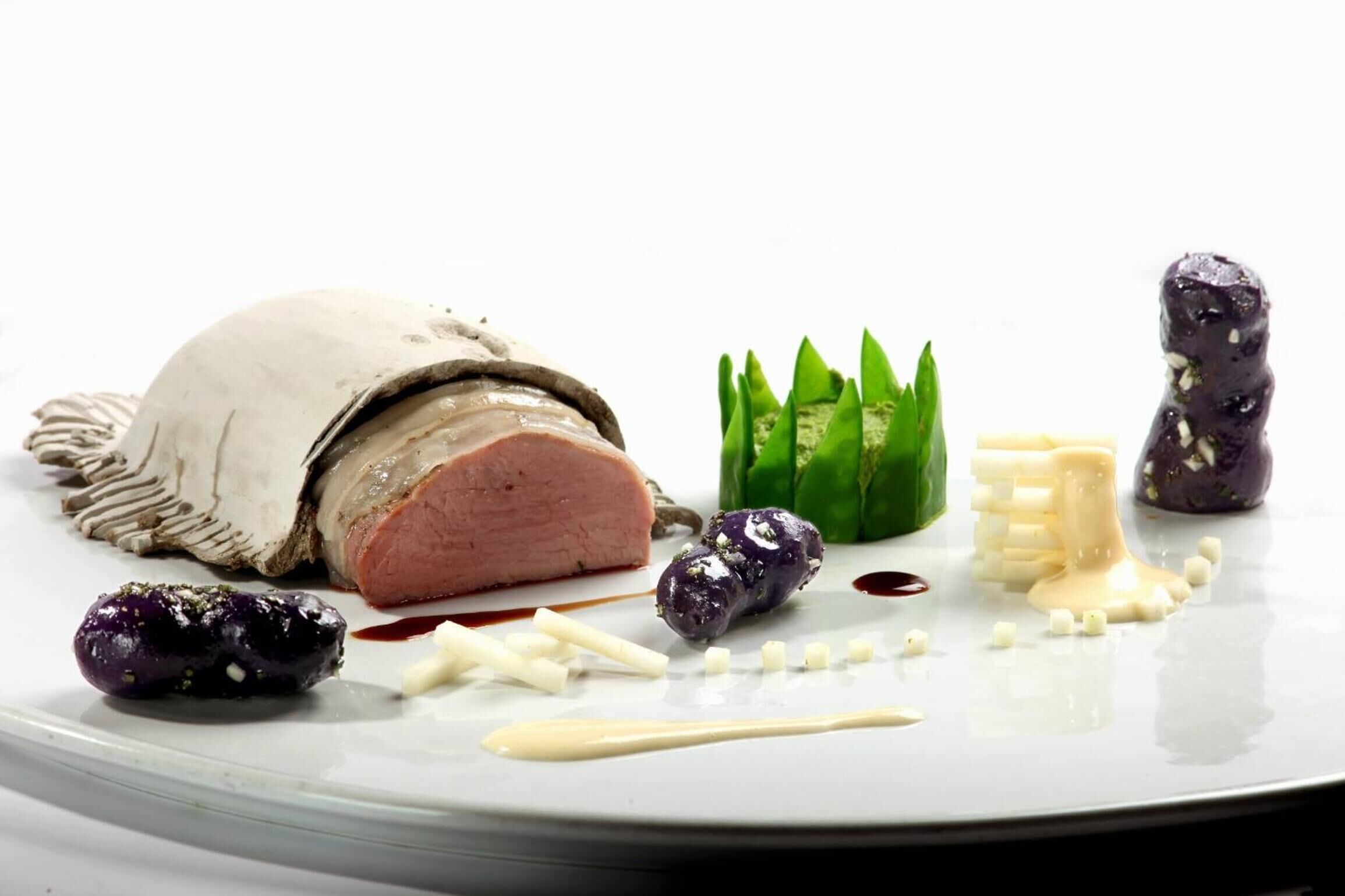 A plate with a slice of meat, green garnish, and various small food items.