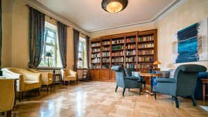 Una biblioteca espaciosa con suelo de madera, varios rincones de descanso y una amplia estantería llena de libros.