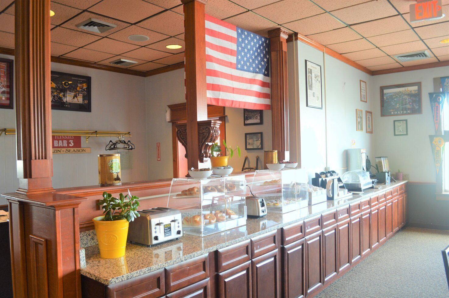 A reception area with a long counter, a large American flag, and a sign for 'Flannies Bar 3'.