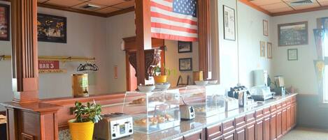 A reception area with a long counter, a large American flag, and a sign for 'Flannies Bar 3'.