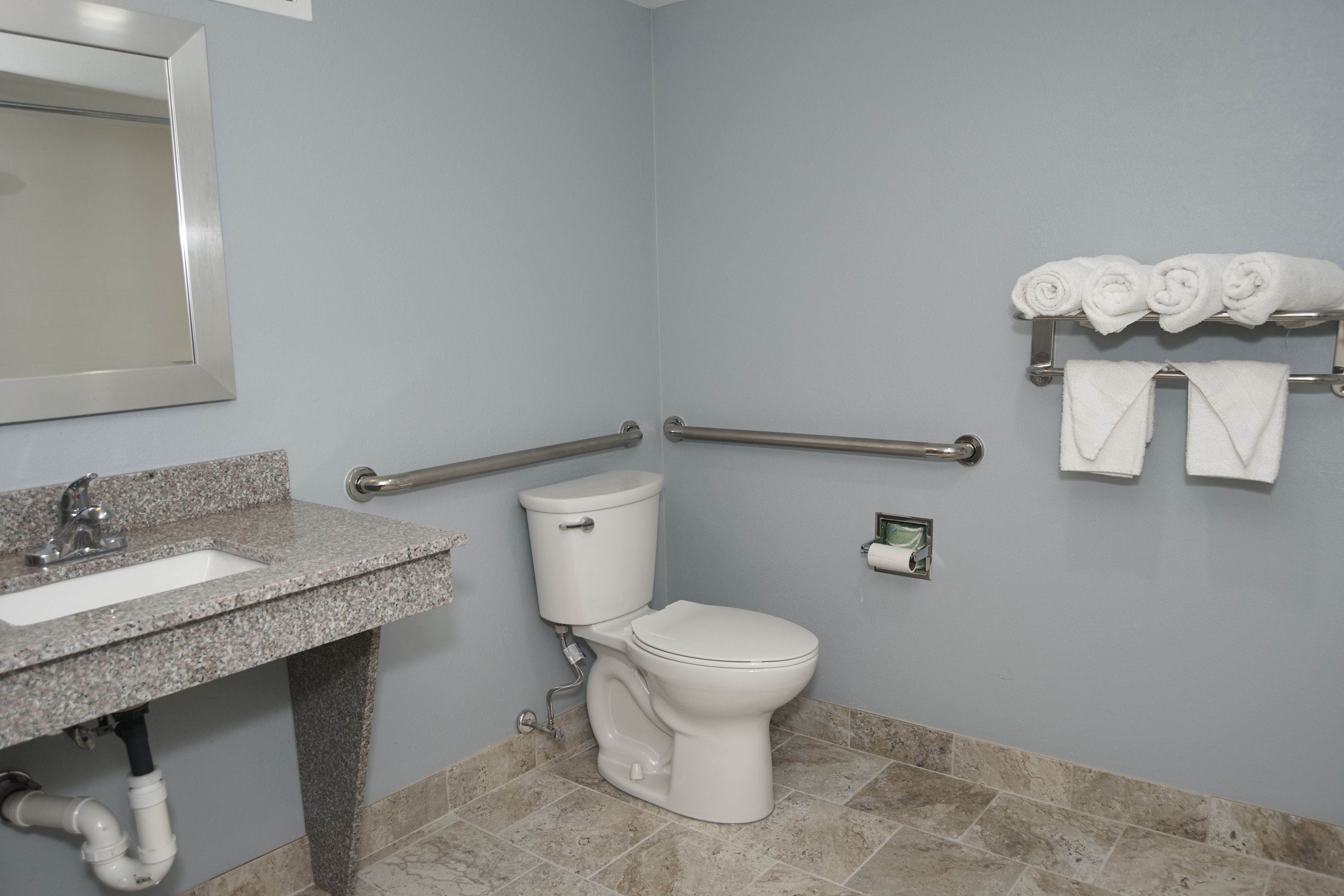 A bathroom with a sink, toilet, and handrails.