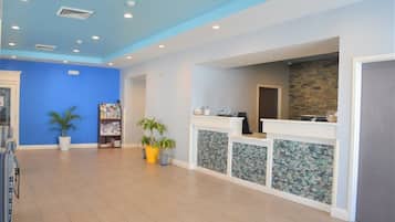 A reception area with a blue wall, a reception desk, and potted plants.