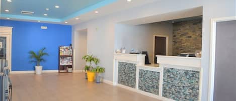 A reception area with a blue wall, a reception desk, and potted plants.